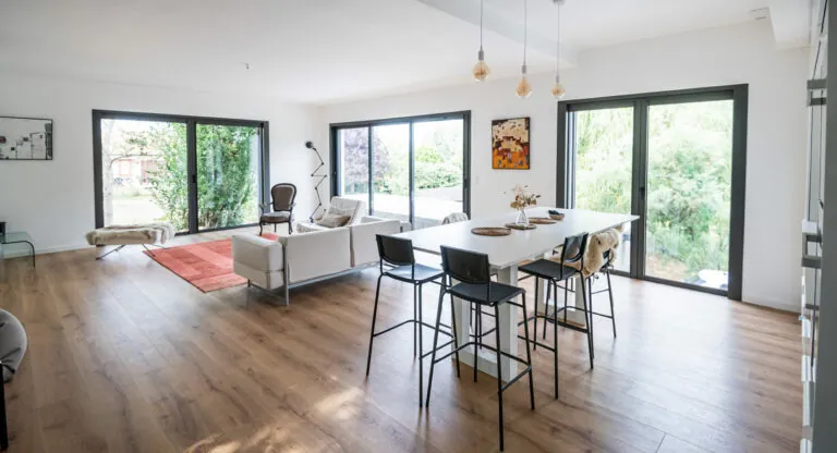 Séjour ouvert sur le jardin par des fenêtres et portes-fenêtres en aluminium anthracite